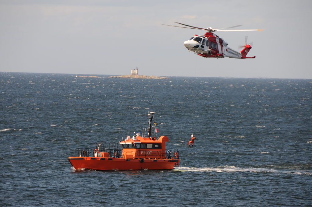 Winschning mellan lotsbåt och Sjöräddninghelikopter. Fyren Tjärven i bakgrunden